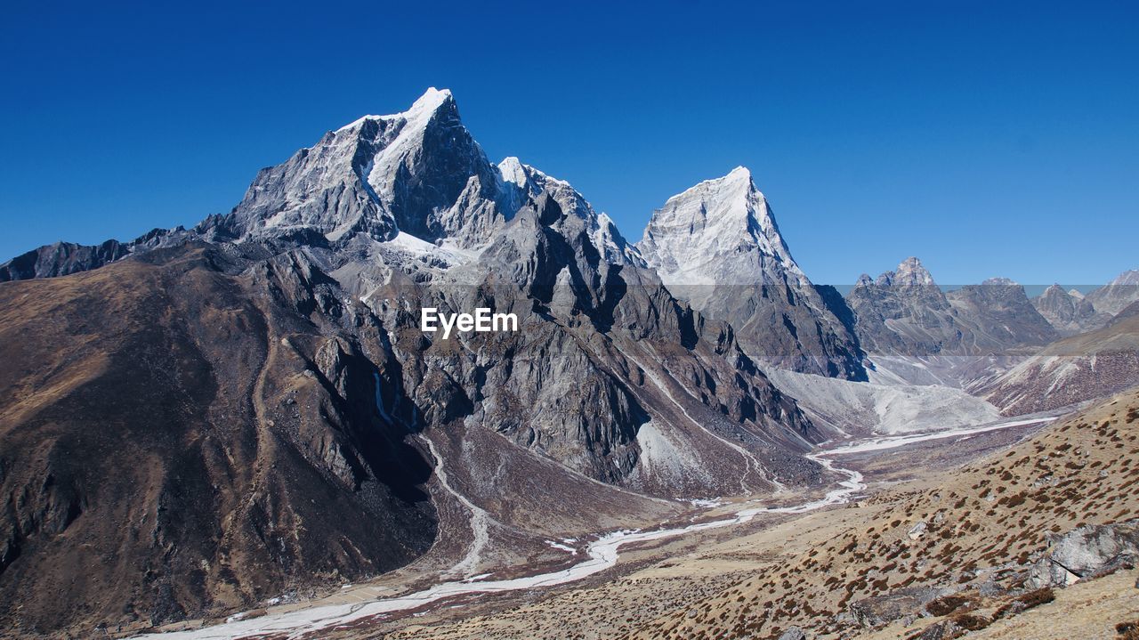 Panoramic view of snowcapped mountains against clear blue sky