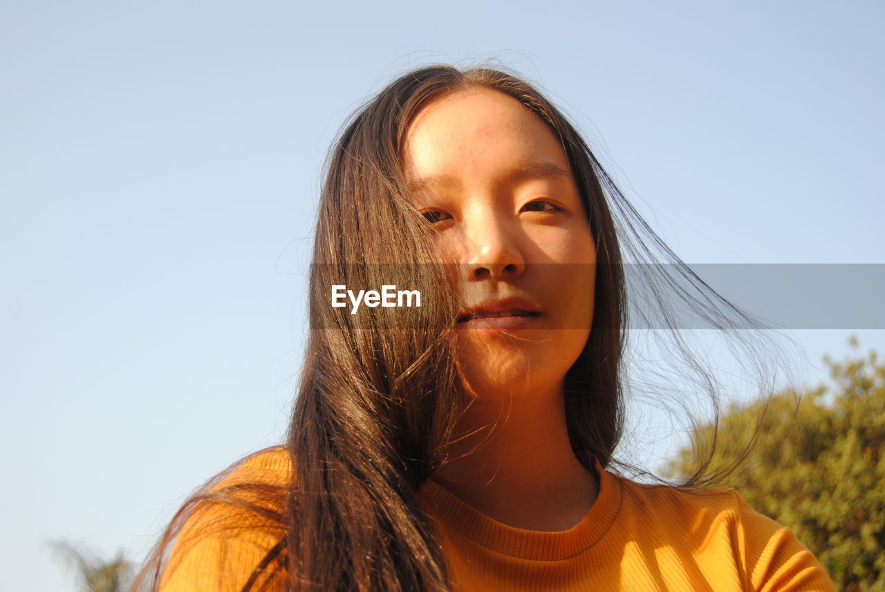 Portrait of beautiful young woman against clear sky