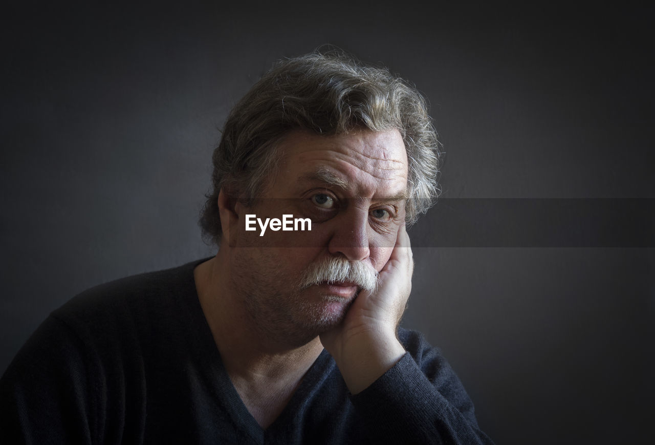 Portrait of thoughtful man against black background