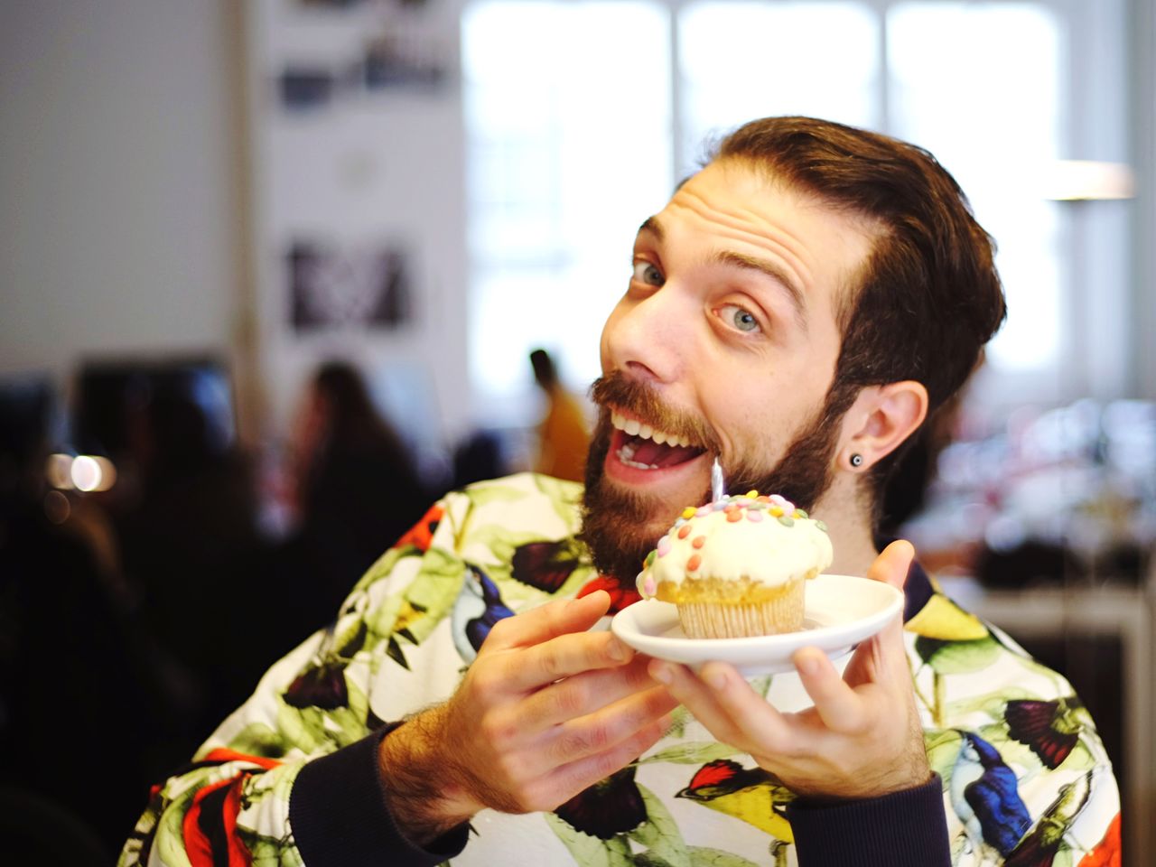 Portrait of cheerful young man holding cupcake during birthday