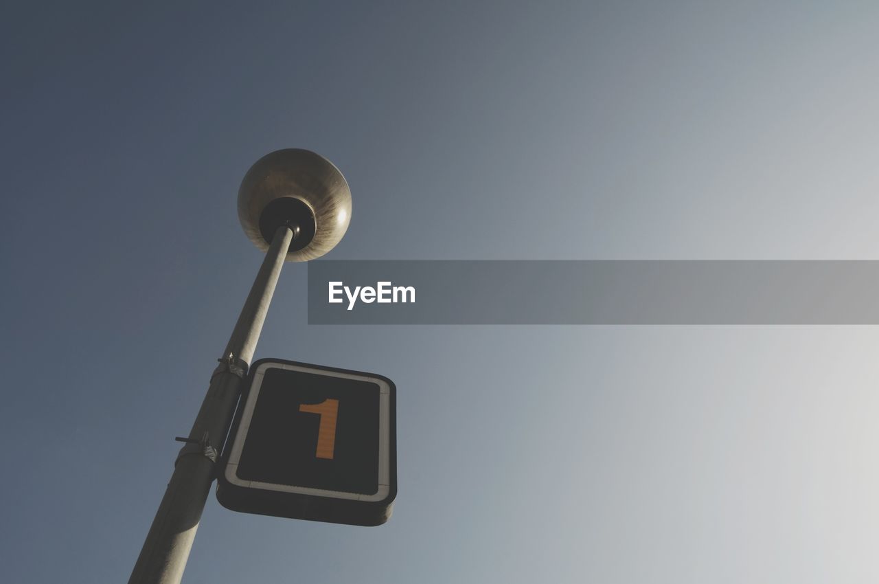 Low angle view of number 1 sign on street light against clear sky