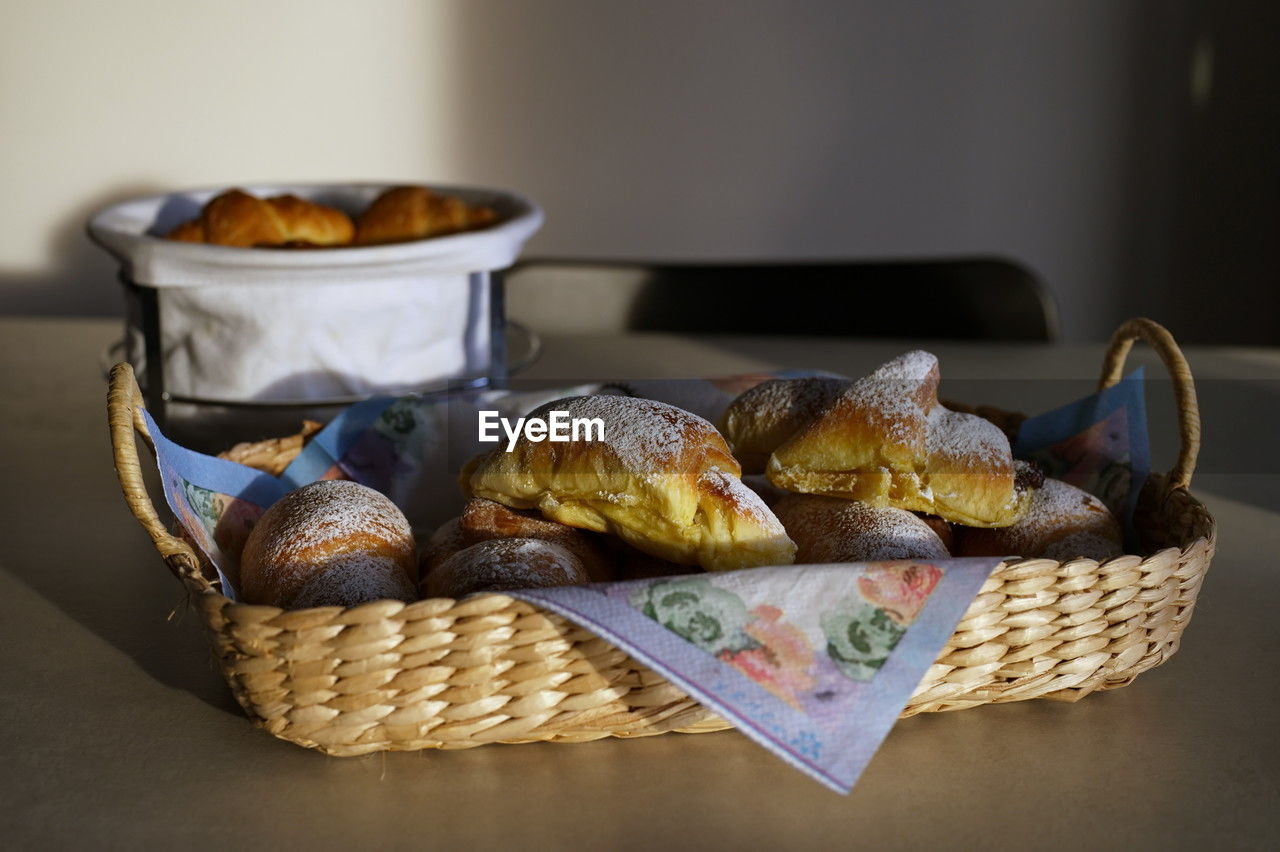 Group of delicious buns in wicker basket on the table lit with setting sun