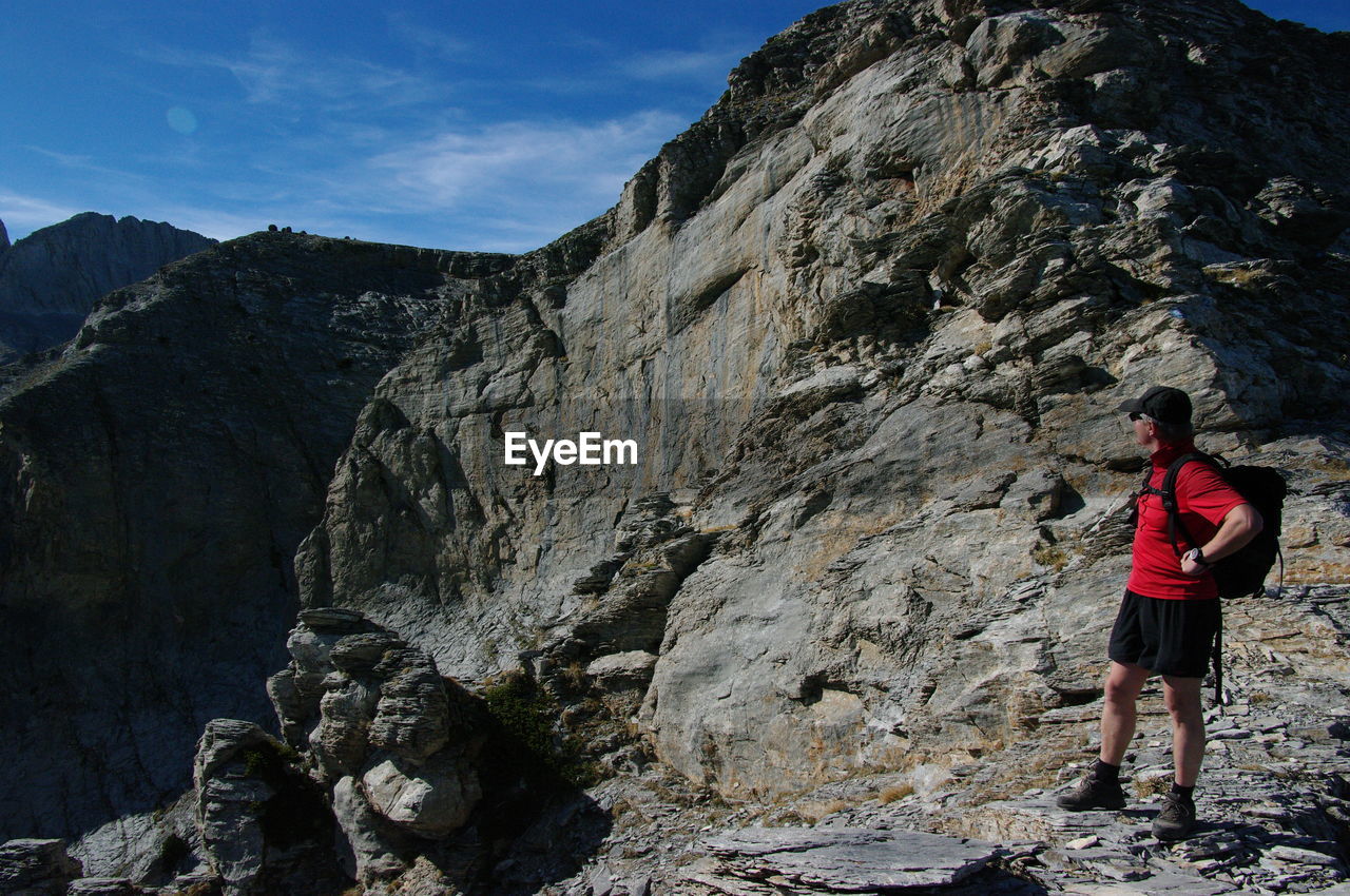 Side view of man standing by rocky mountains