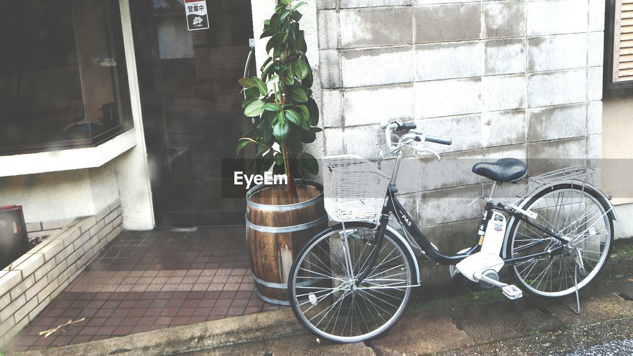 BICYCLE PARKED AGAINST WALL IN CITY