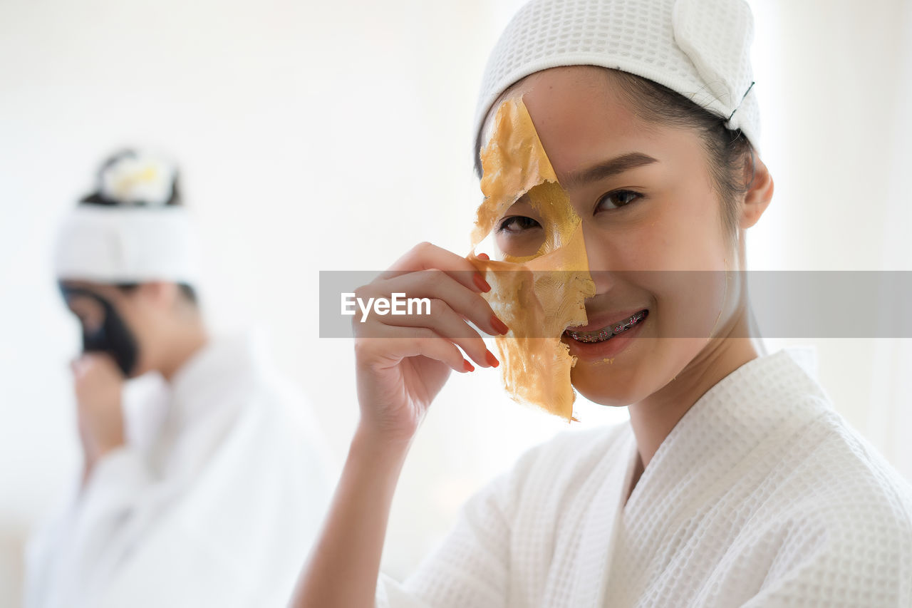 Young woman removing facial mask from face in spa