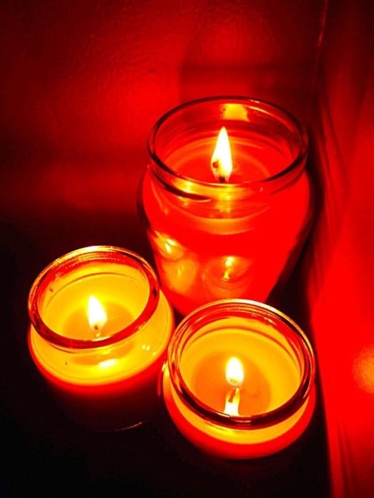 CLOSE-UP OF LIT TEA LIGHT CANDLES IN ROOM