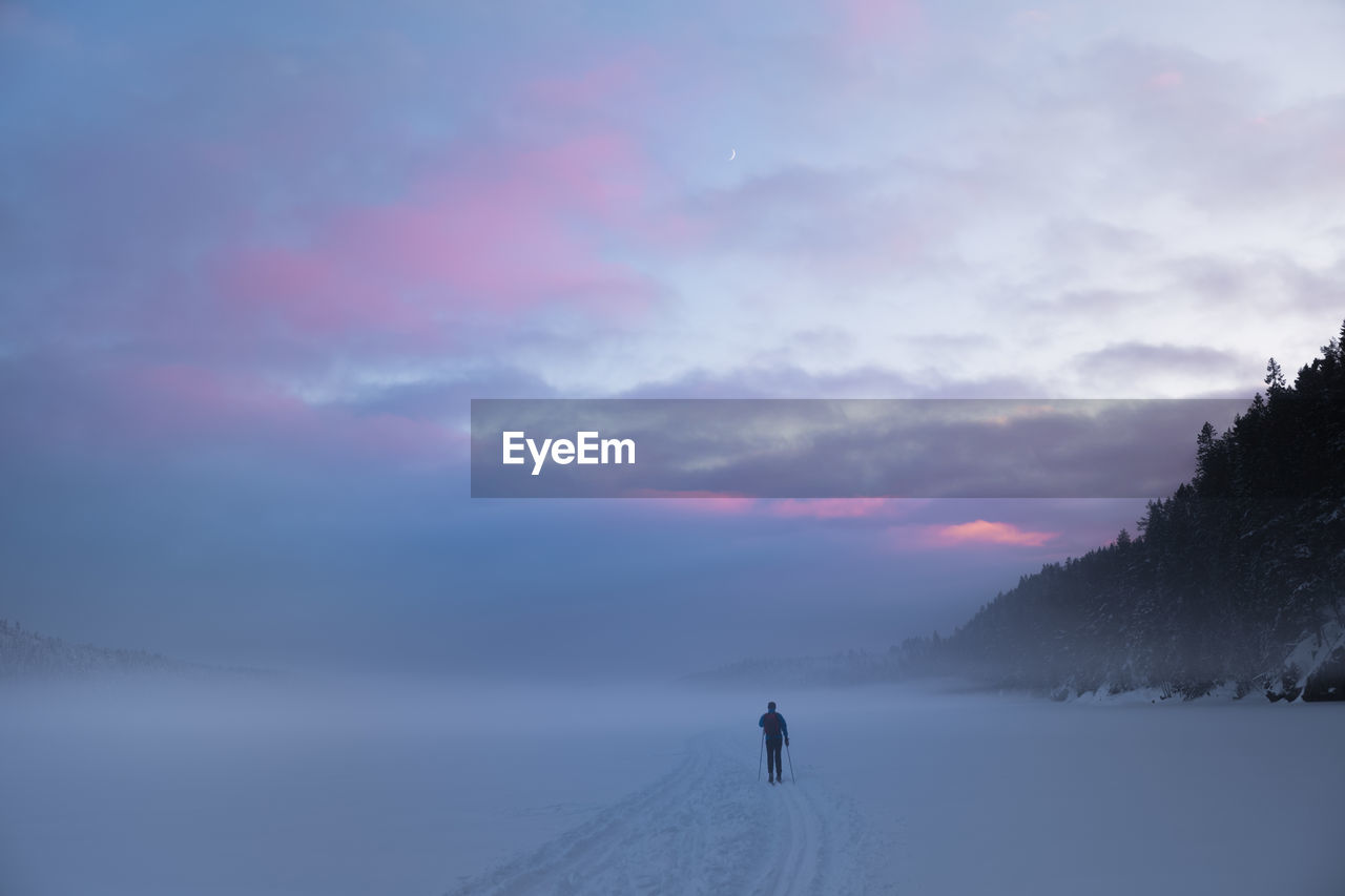 Rear view of man on snow during sunset