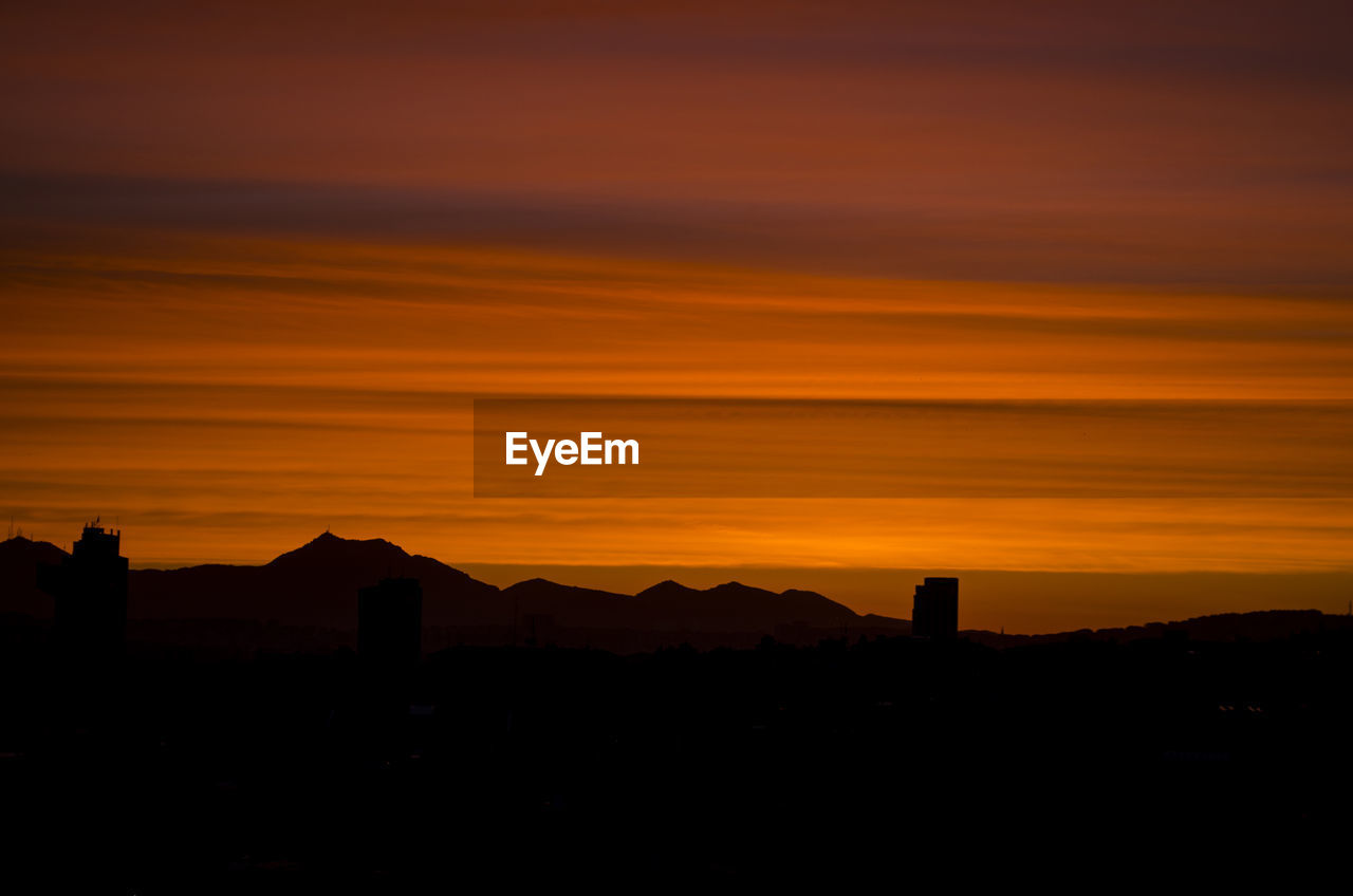 SILHOUETTE OF MOUNTAIN AGAINST DRAMATIC SKY