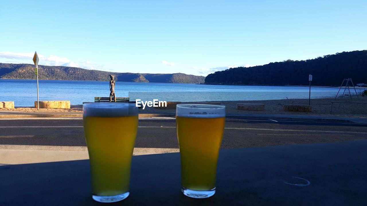 Close-up of beer on table by sea against clear sky