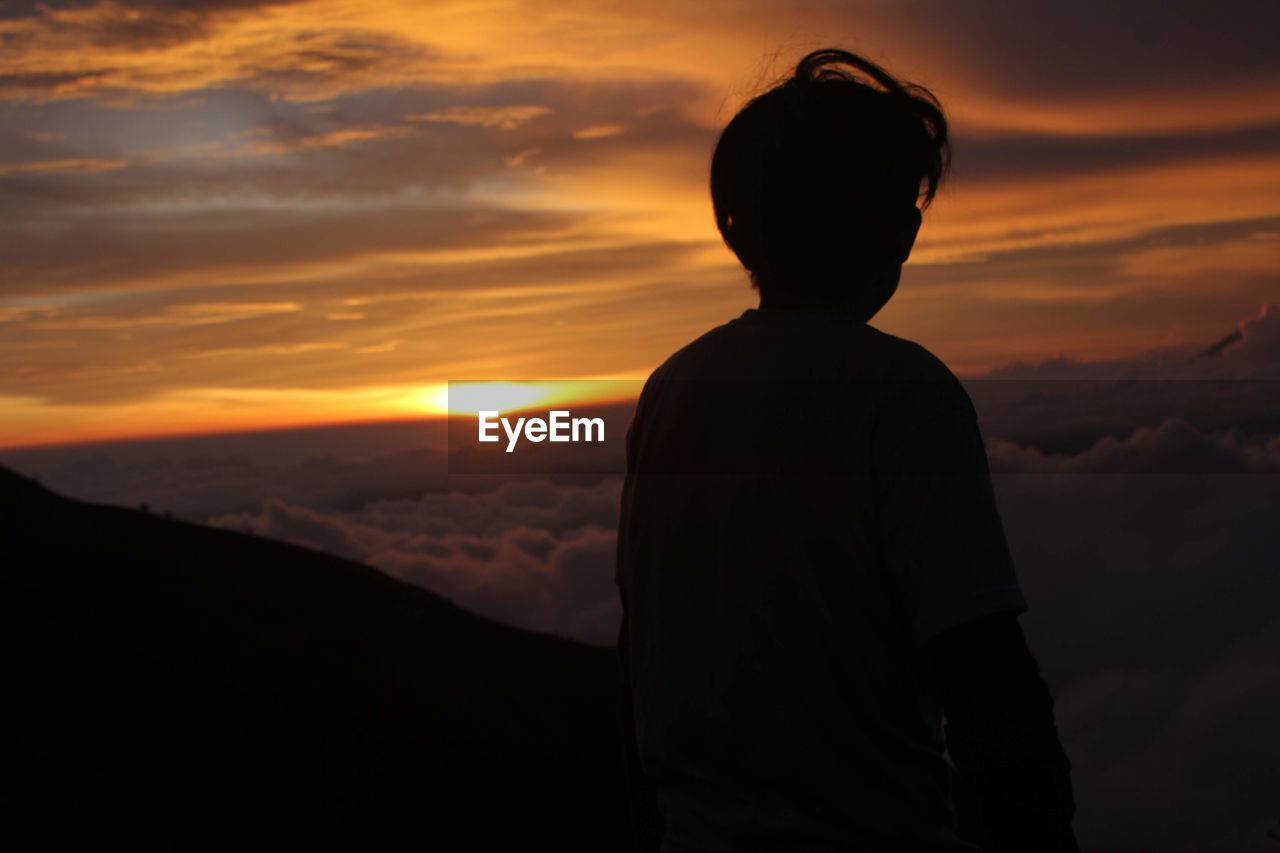 Rear view of silhouette man standing against sky during sunset