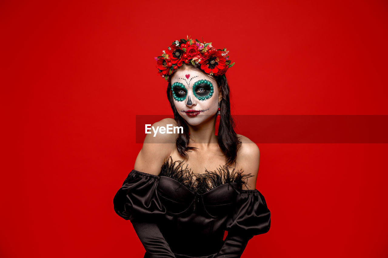 portrait of young woman standing against red background