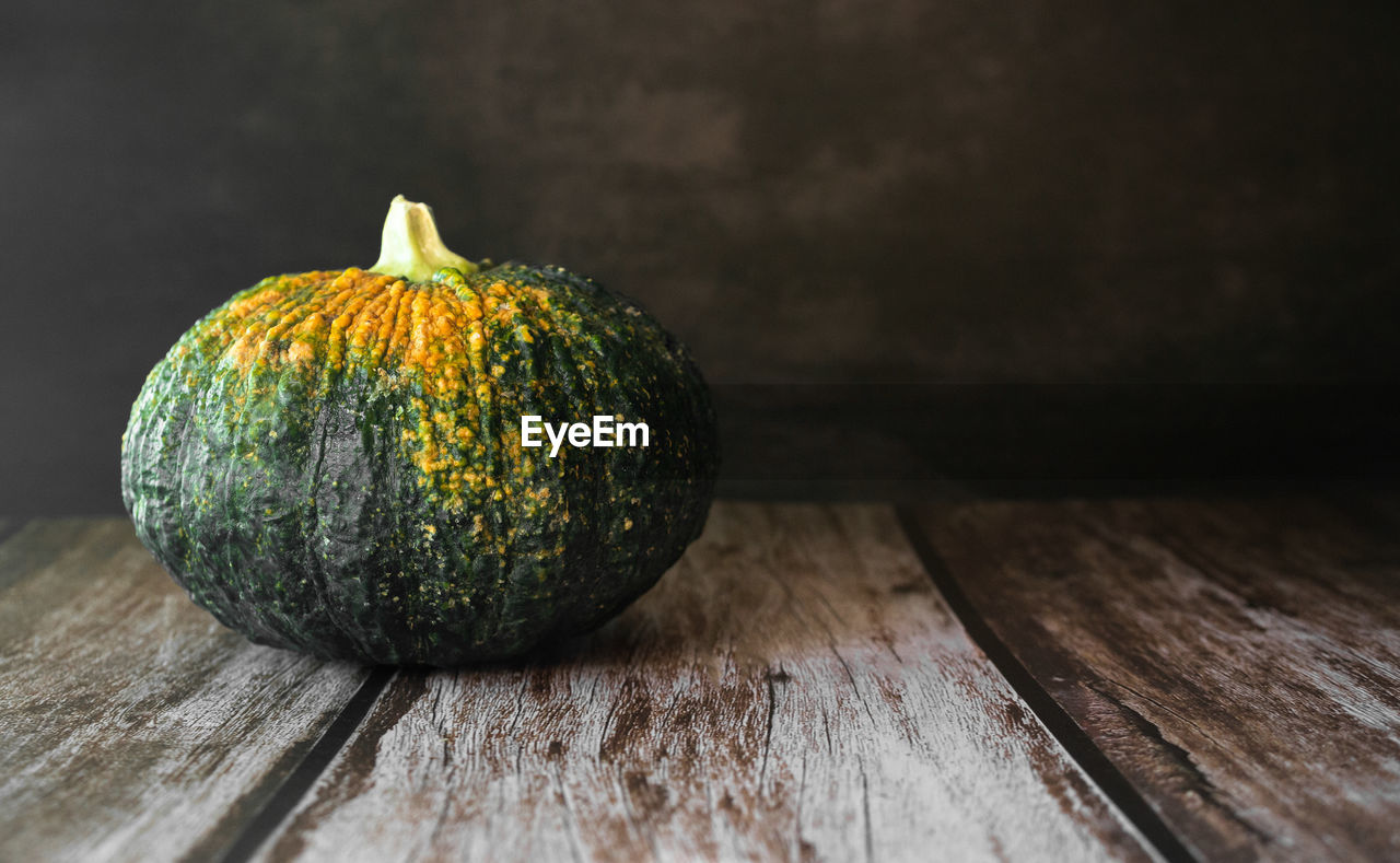 CLOSE-UP OF PUMPKIN ON WOODEN TABLE