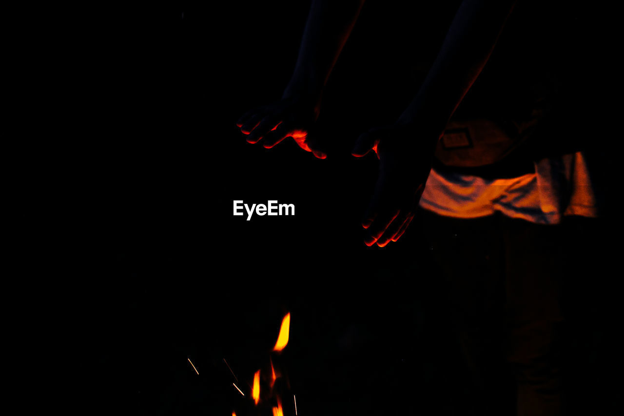 High angle view of hands by campfire