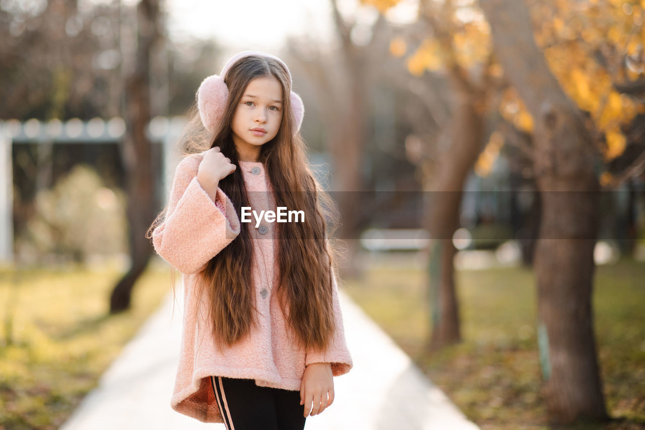 Cute kid girl 10-12 year old with long blonde hair wear fluffy headband earphones and pink jacket