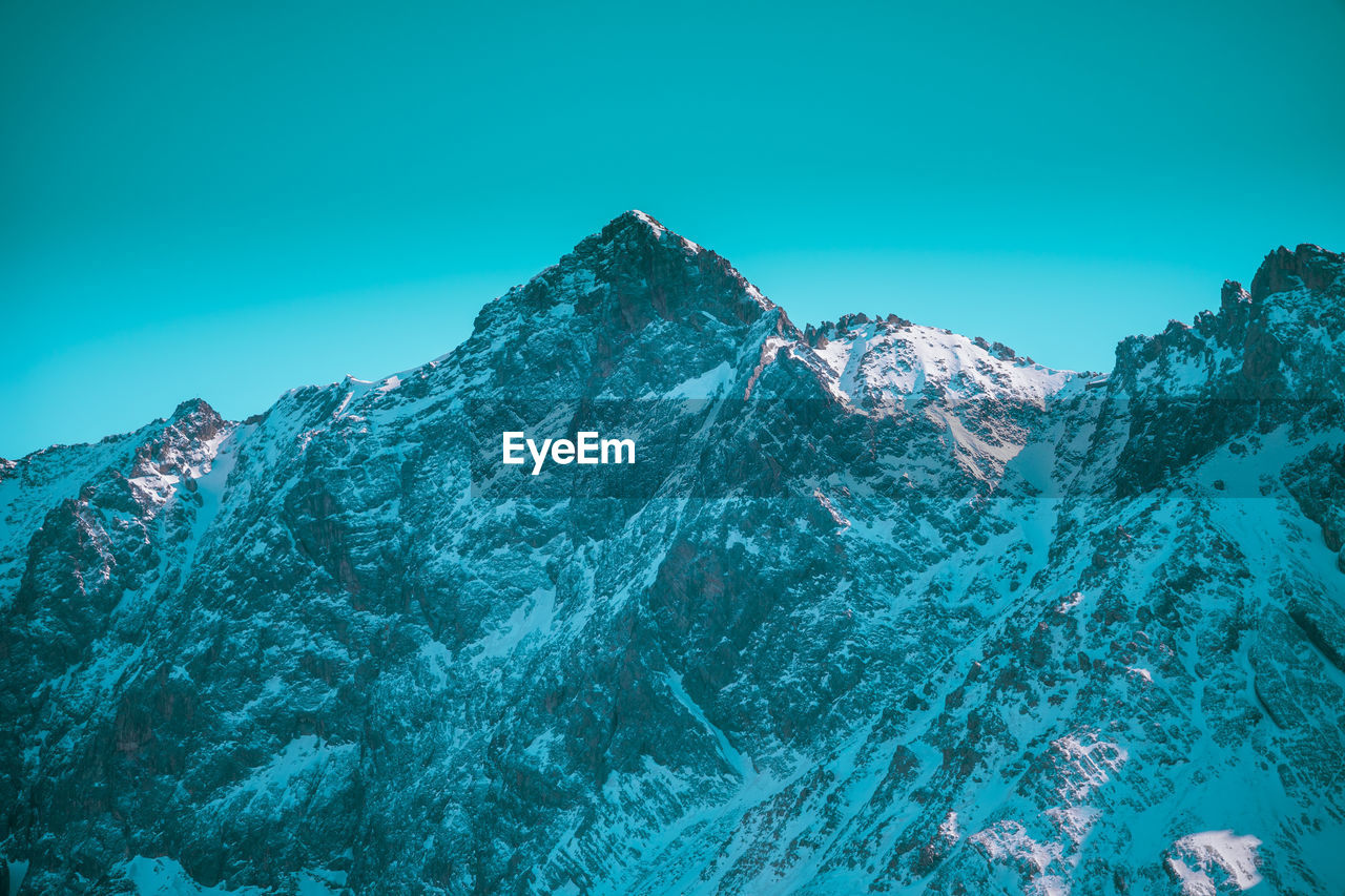 Scenic view of snowcapped mountains against clear blue sky