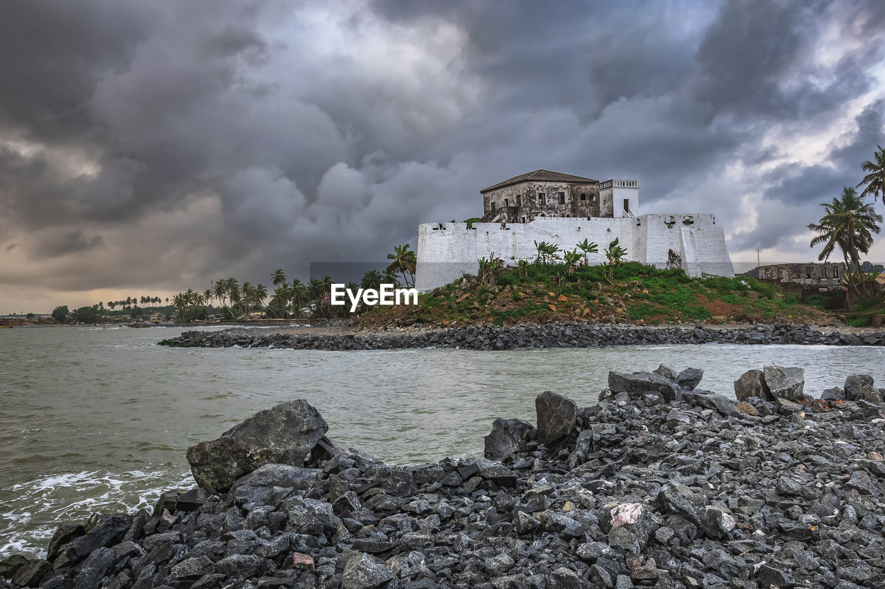 cloud, water, coast, architecture, sky, shore, sea, built structure, land, ocean, building exterior, beach, nature, building, travel destinations, storm, rock, environment, travel, wave, storm cloud, tourism, coastline, dramatic sky, landscape, beauty in nature, bay, no people, outdoors, scenics - nature, city, overcast, history, holiday, house, trip, the past, vacation, cloudscape, tropical climate, tree, horizon, island