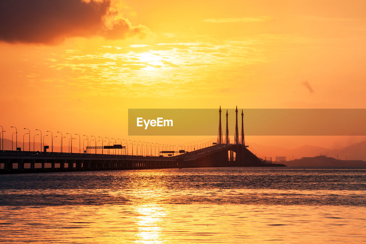 View of suspension bridge over river during sunset