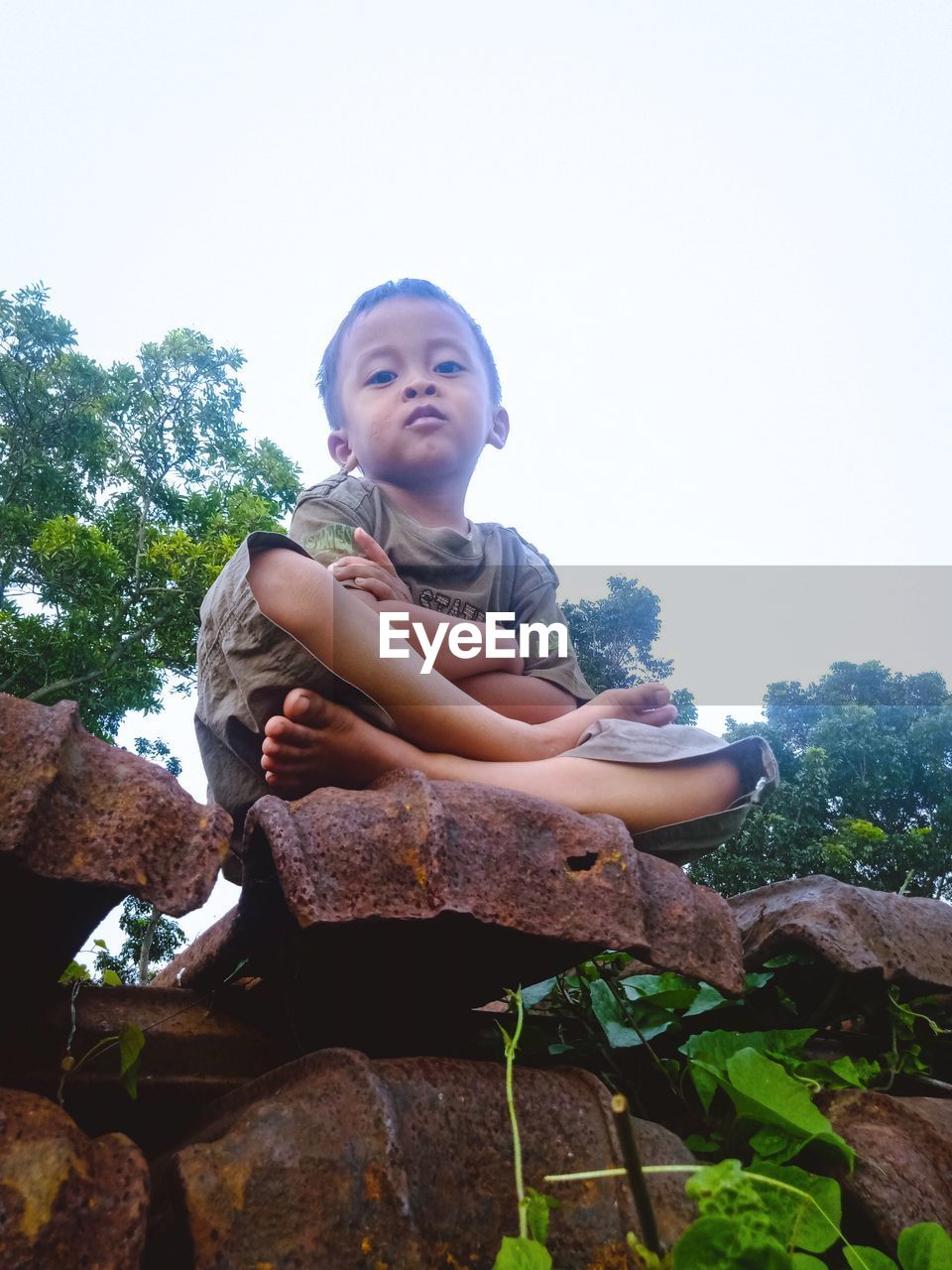 PORTRAIT OF BOY SITTING ON ROCK