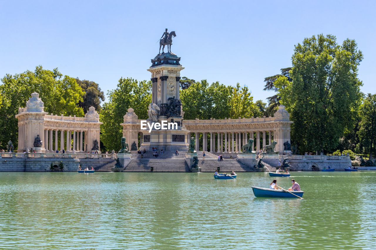 People rowing boats on a lake at retiro park in madrid, spain