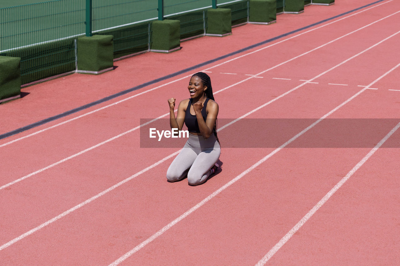 Black professional female athlete in sportswear rejoices with success in long-distance race on track