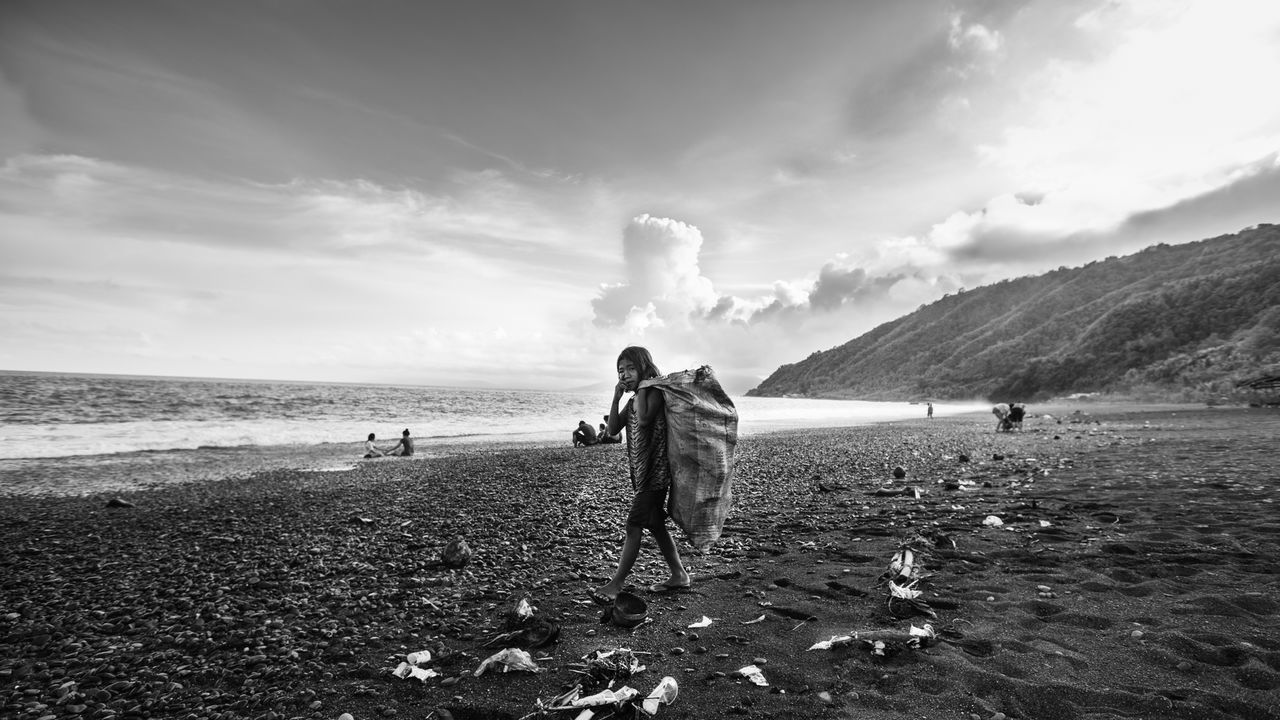 Boy standing on beach against sky