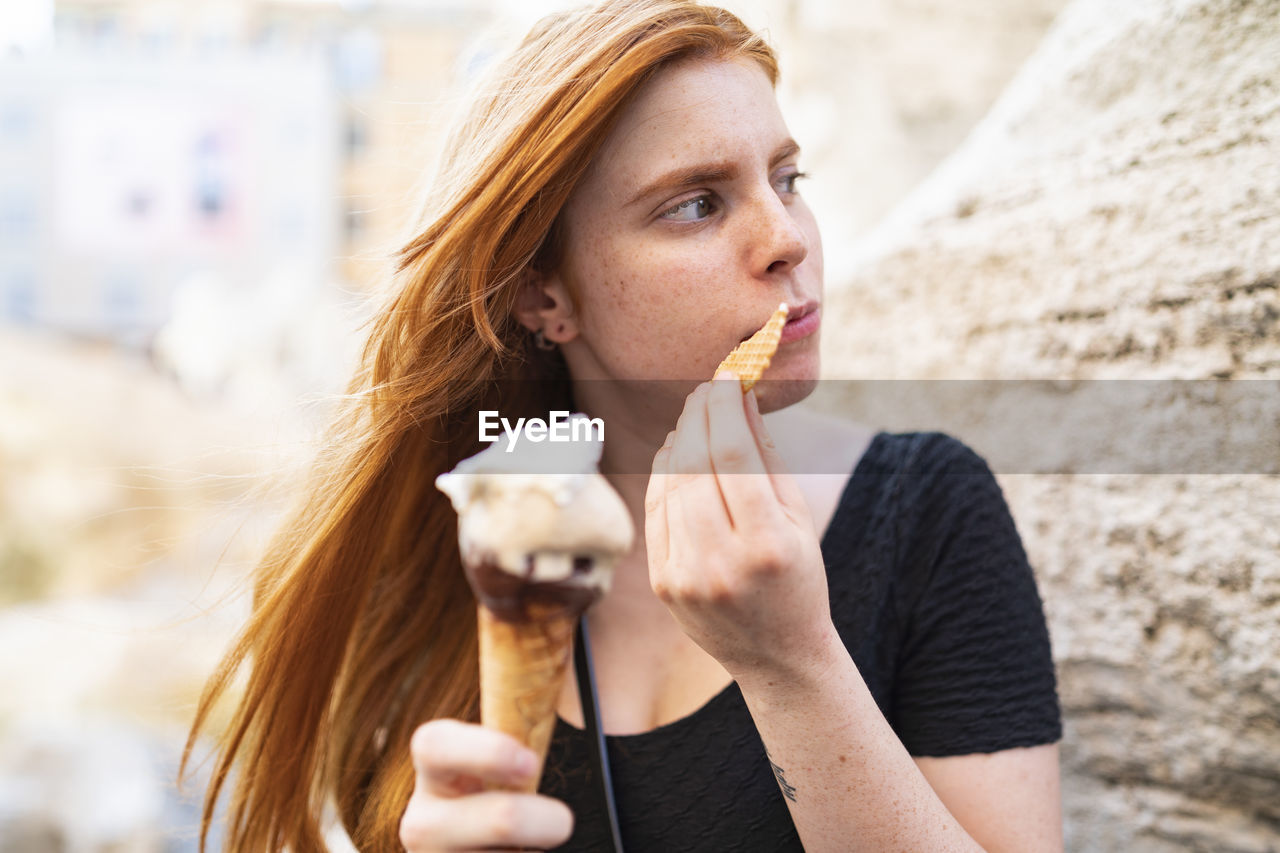 Young woman eating ice cream waffle cone