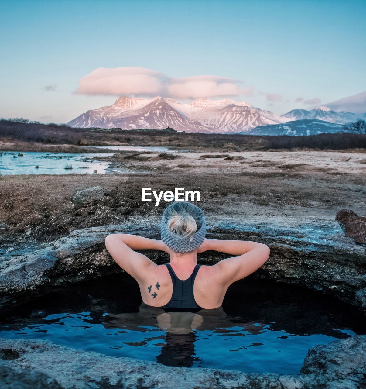 WOMAN WITH ARMS RAISED AGAINST MOUNTAIN RANGE