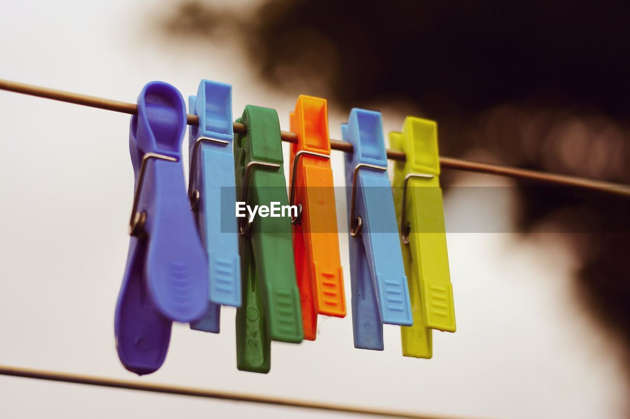 Close-up of colorful pegs hanging on clothesline