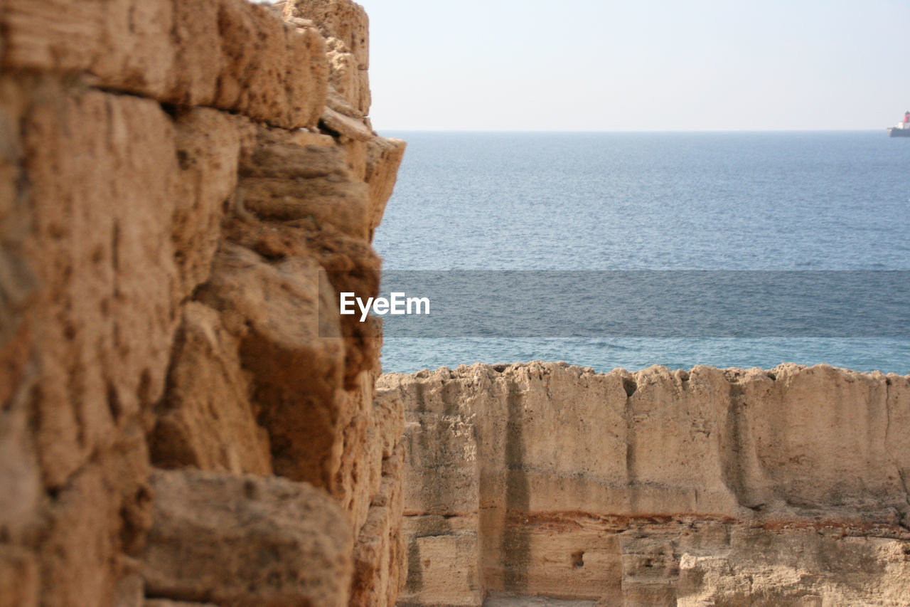 Rock formation by sea against clear sky