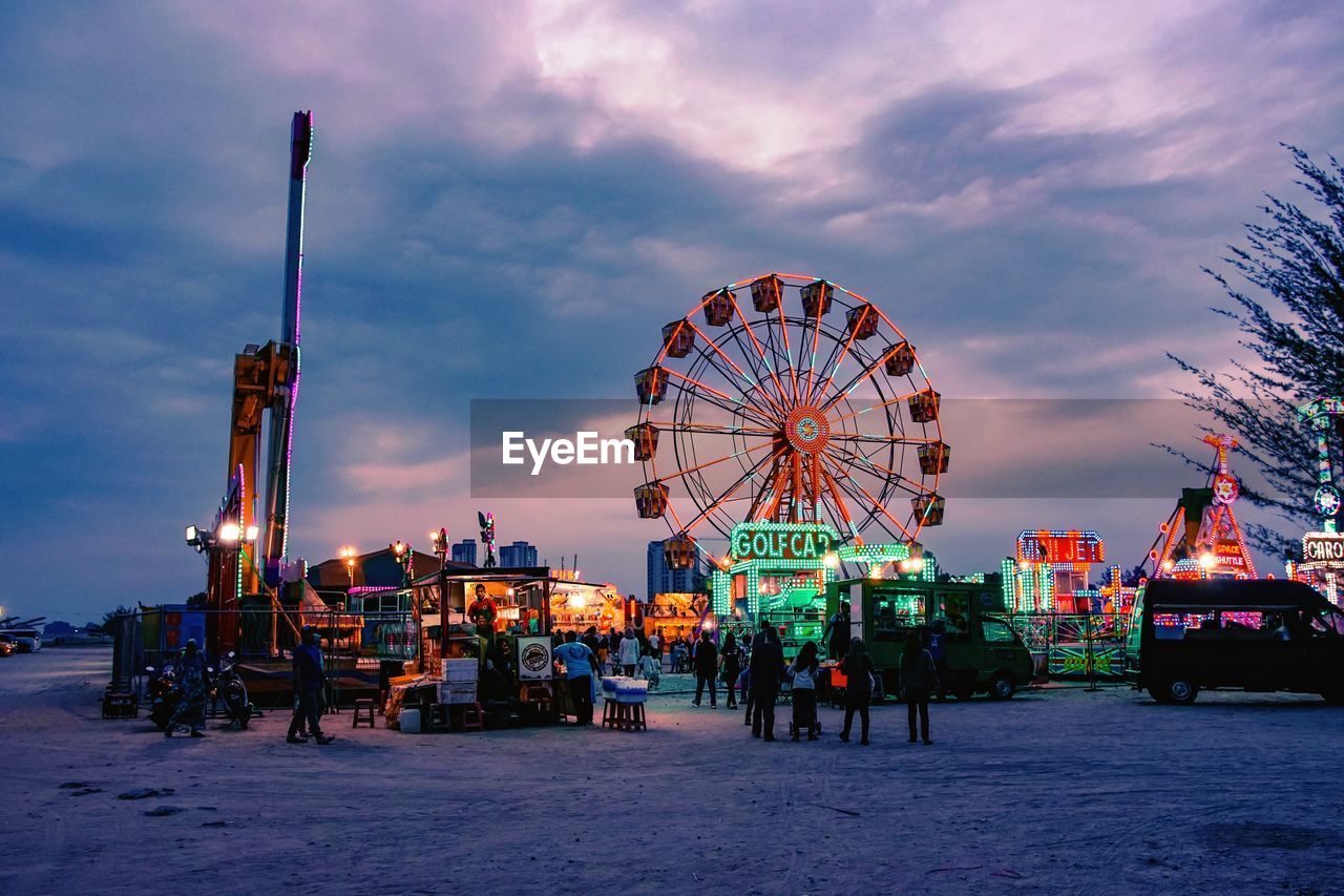 Illuminated ferris wheel against sky at dusk