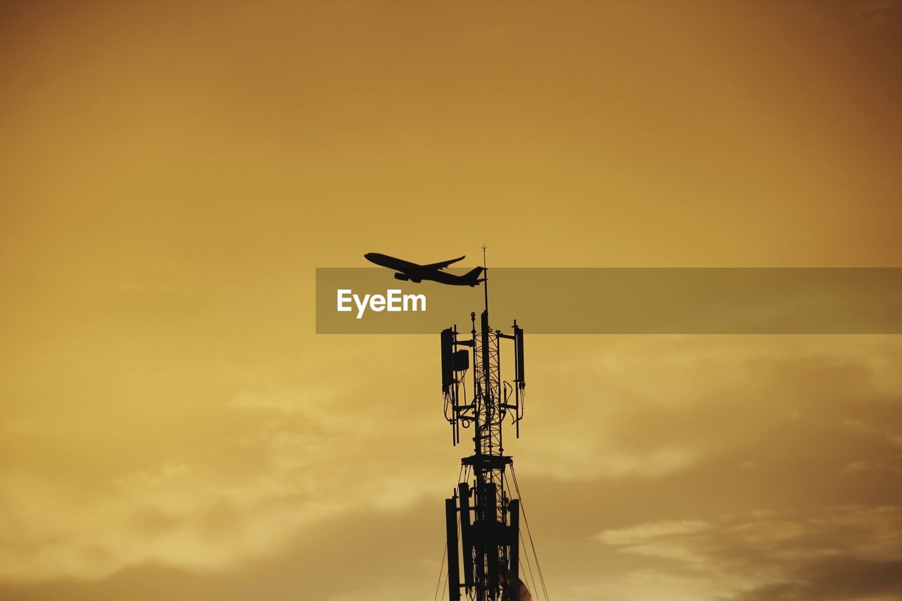 Low angle view of communications tower against sky during sunset