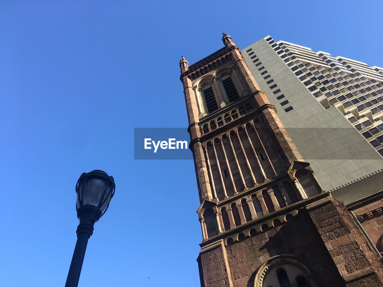 LOW ANGLE VIEW OF STREET LIGHT BY BUILDING AGAINST CLEAR SKY