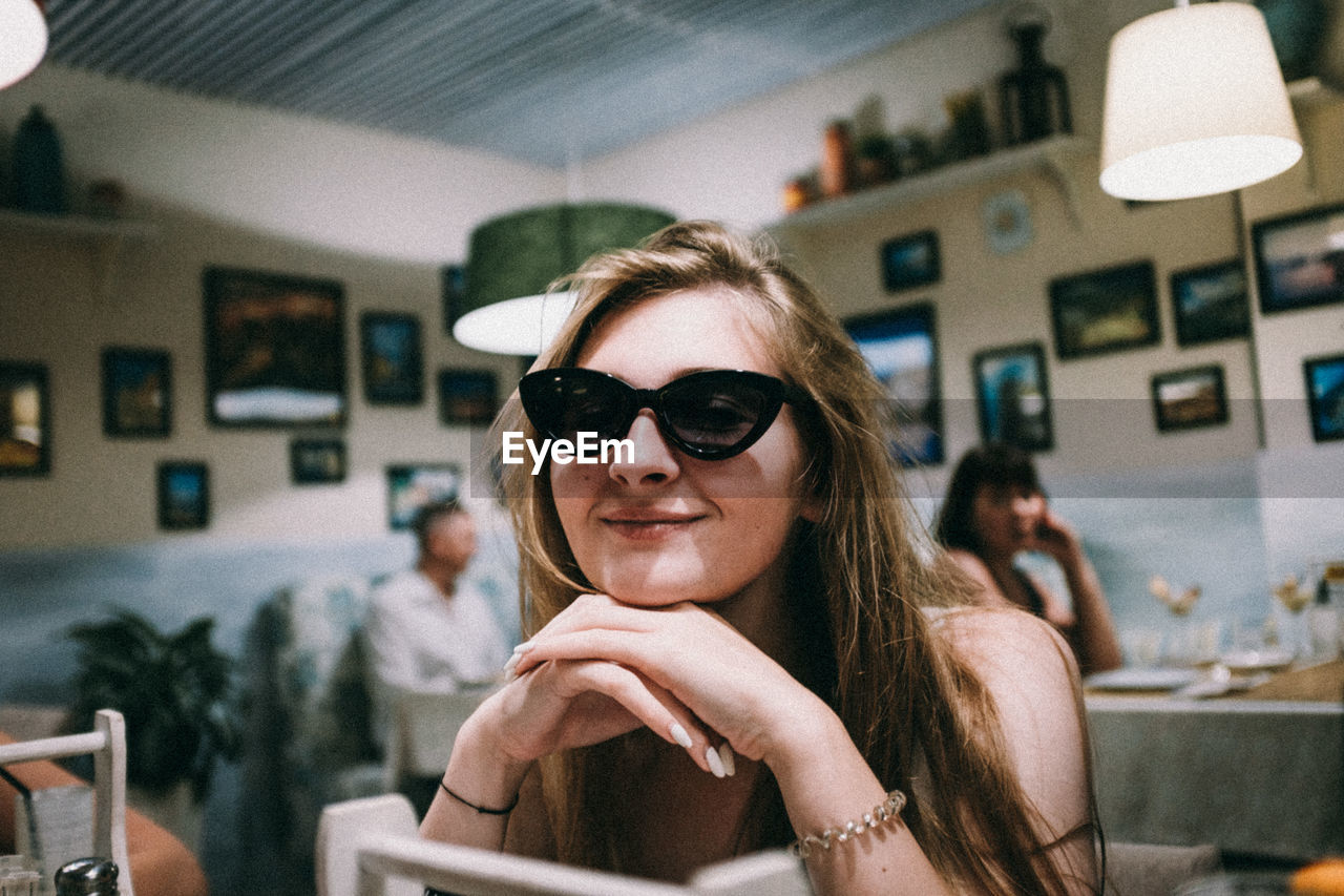 Portrait of young woman in sunglasses at cafe