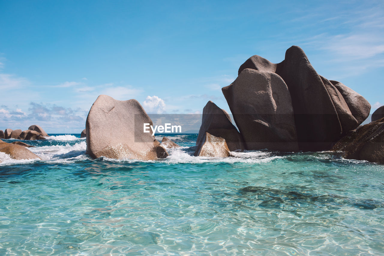 Rock formations in sea against blue sky