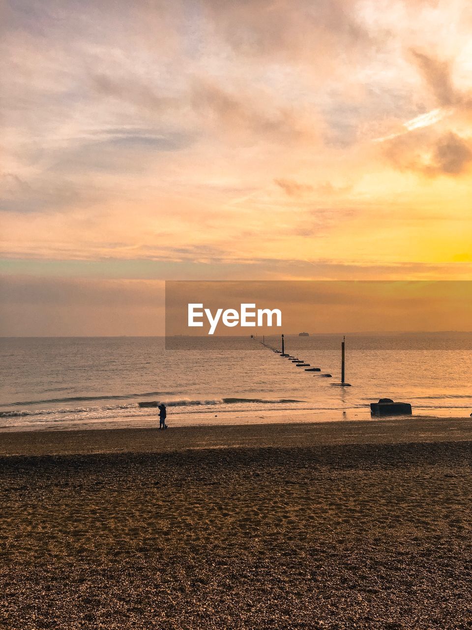 Scenic view of sea against cloudy sky during sunset