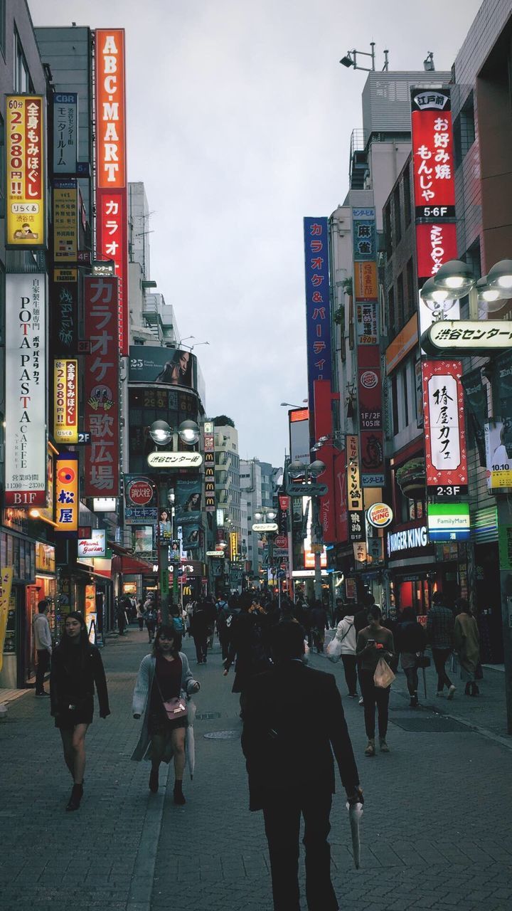 PEOPLE WALKING ON ILLUMINATED STREET