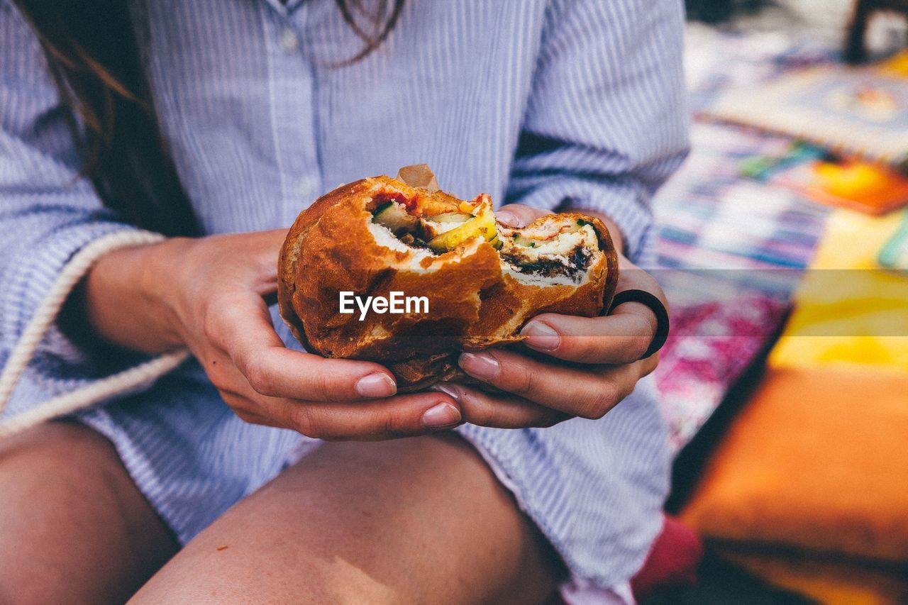 Midsection of woman holding burger