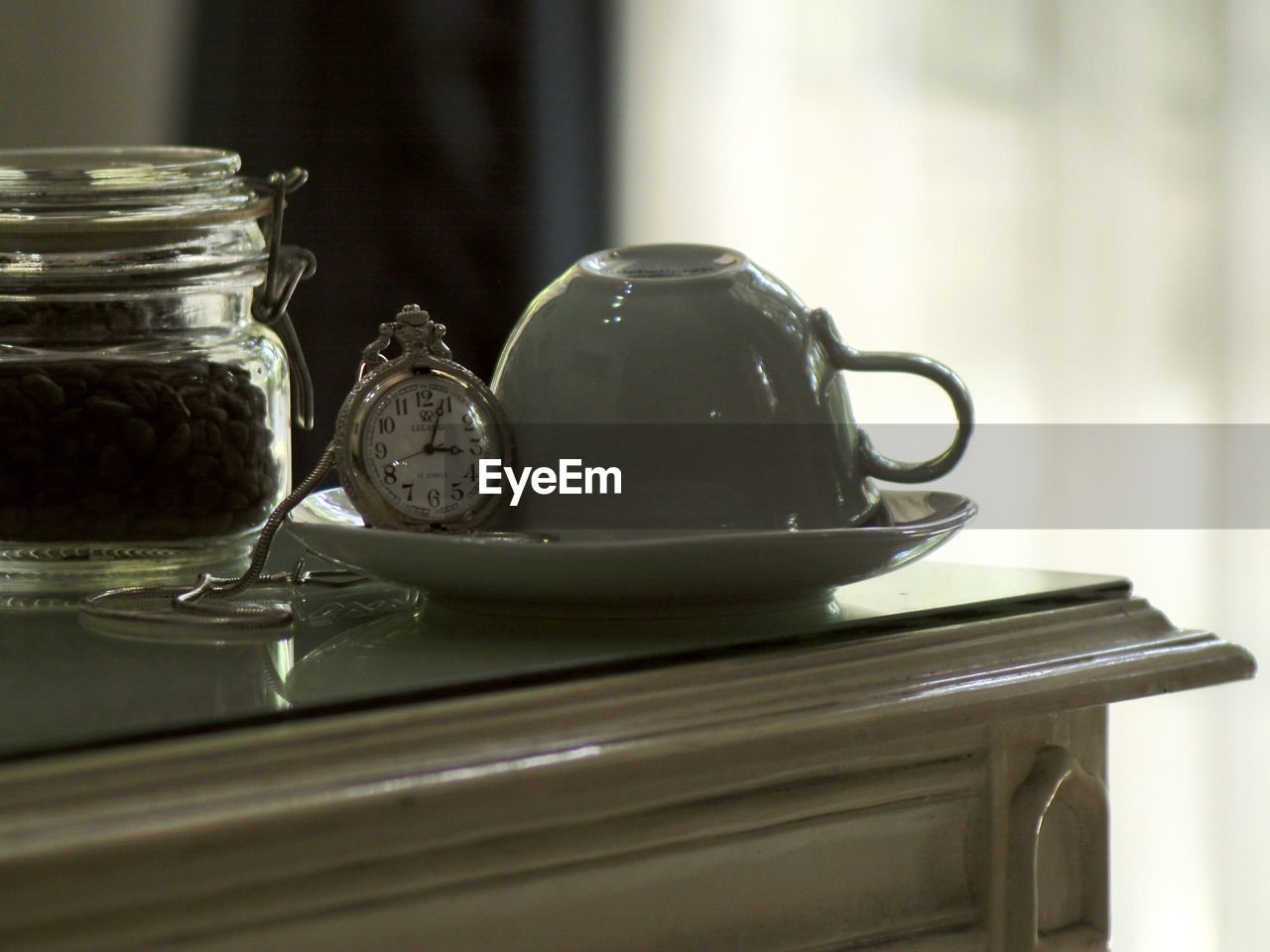 Close-up of pocket watch and cup on saucer