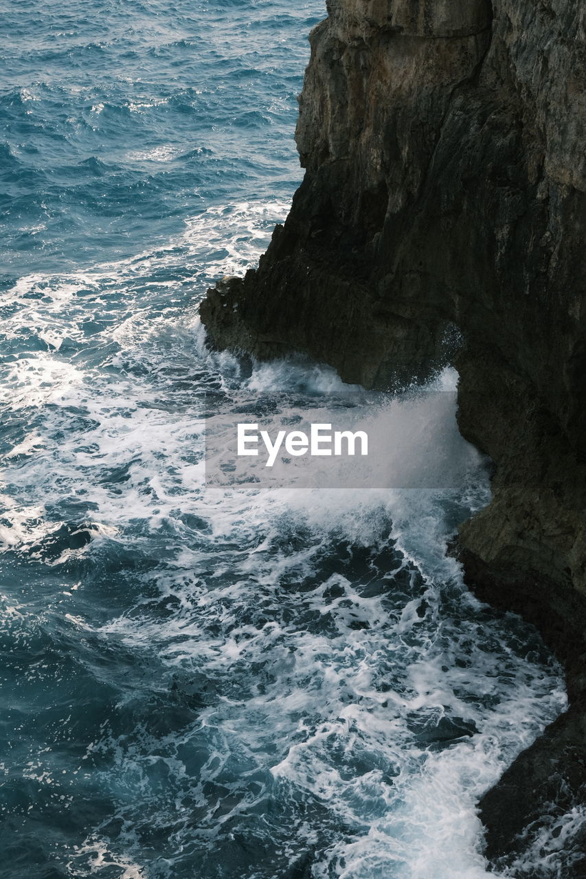 Scenic view of azure sea waves hitting the cliff in the mediterranean 