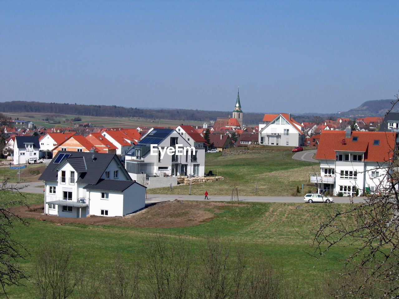 HOUSES AGAINST CLEAR SKY WITH GREEN LANDSCAPE IN BACKGROUND