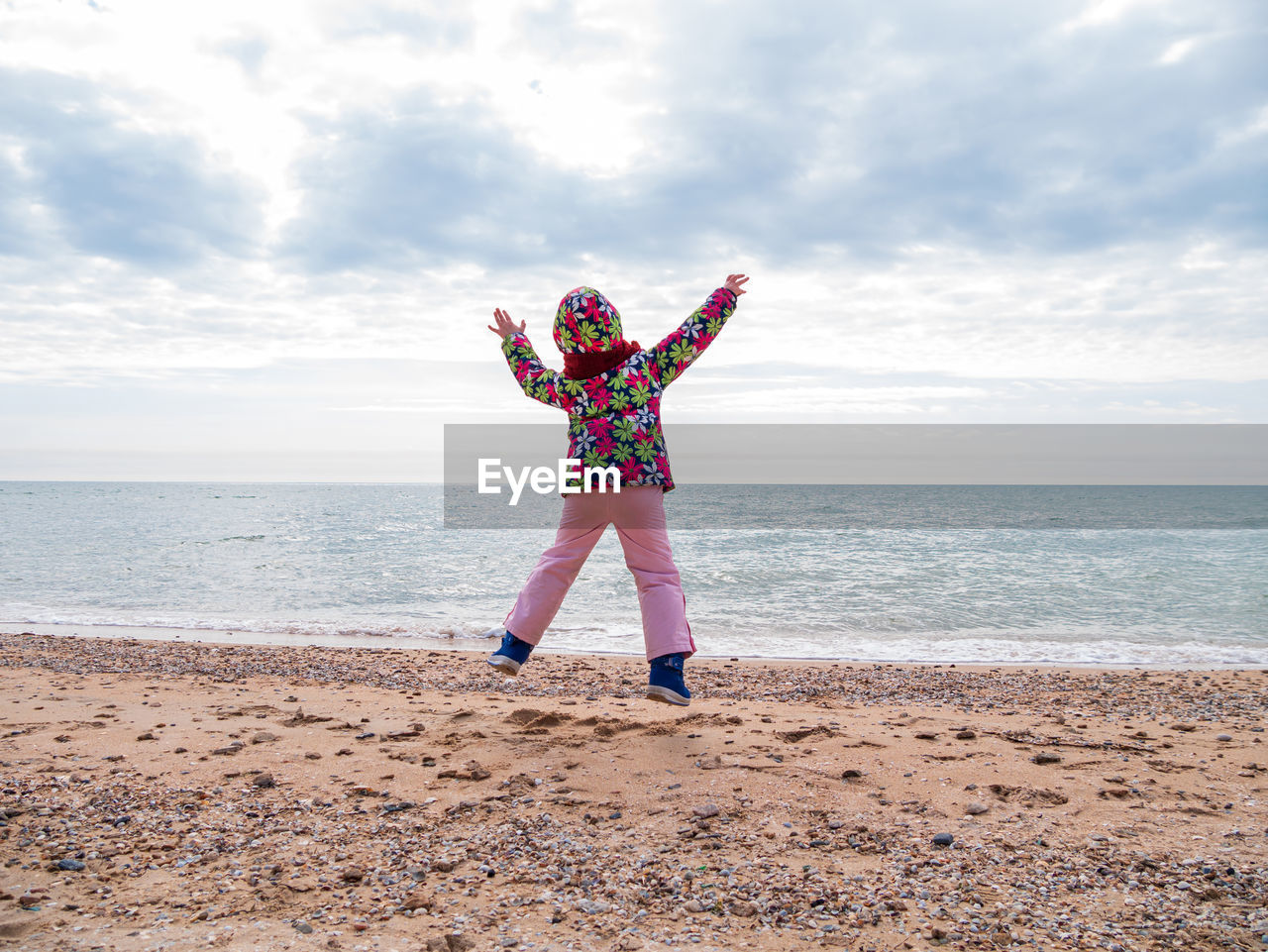Little girl jumping on empty beach flying in the air lifestyle people scenic landscape active family