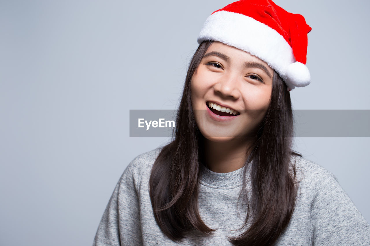 Portrait of smiling young woman against gray background