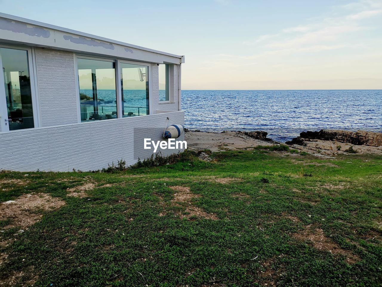 Scenic view of house and sea against sky