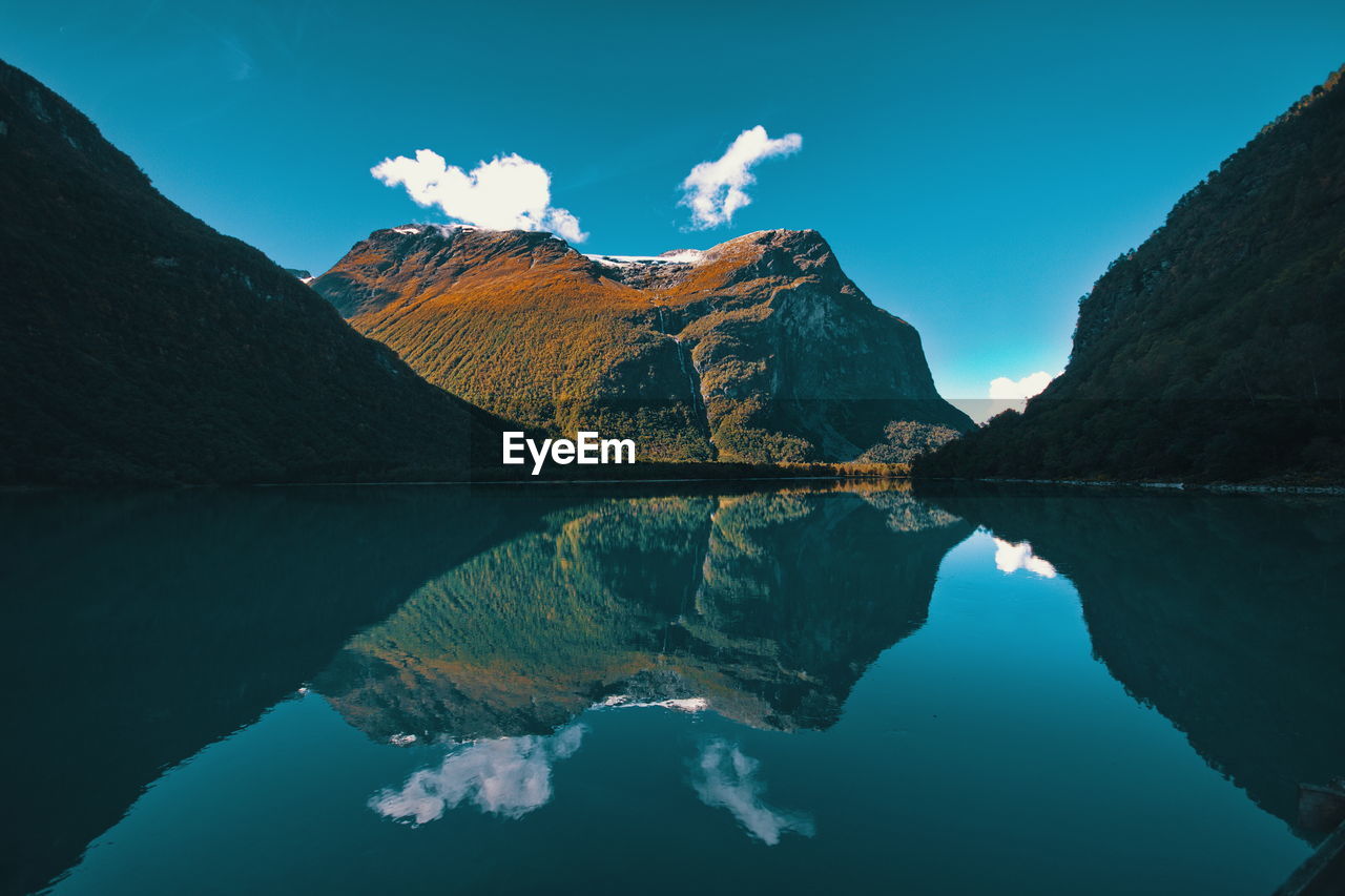 Scenic view of lake and mountains against blue sky