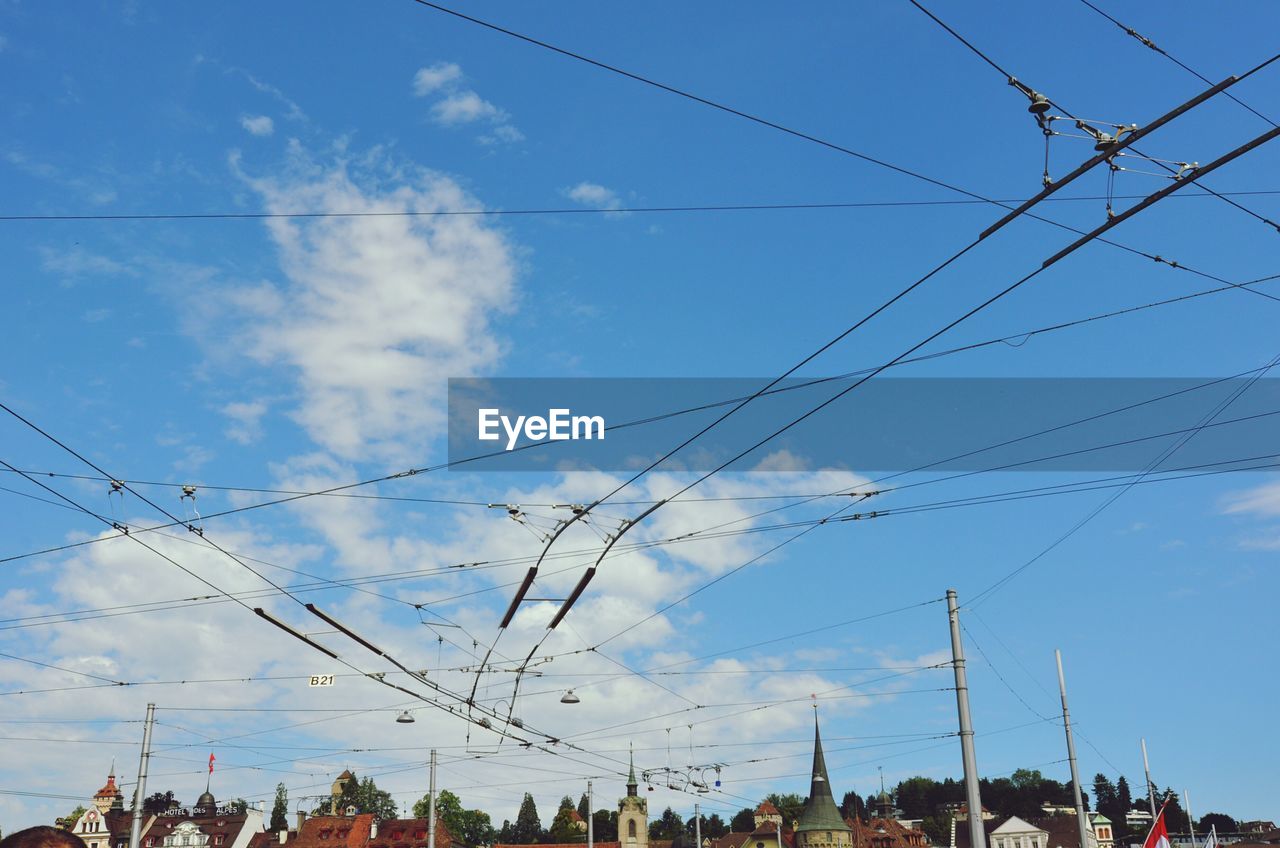 Low angle view of buildings and cables against sky