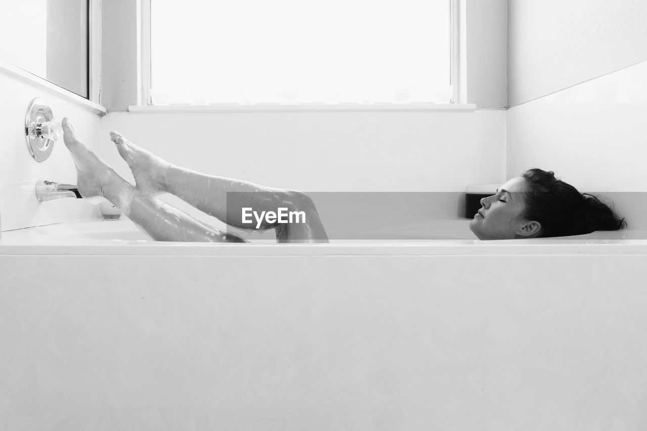 Full length of woman relaxing in bathtub