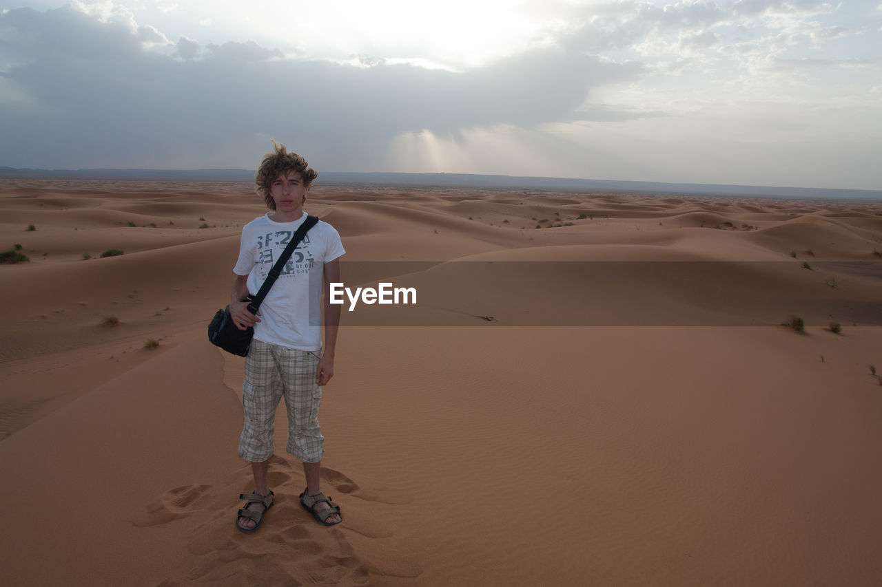 Full length portrait of young man standing in desert