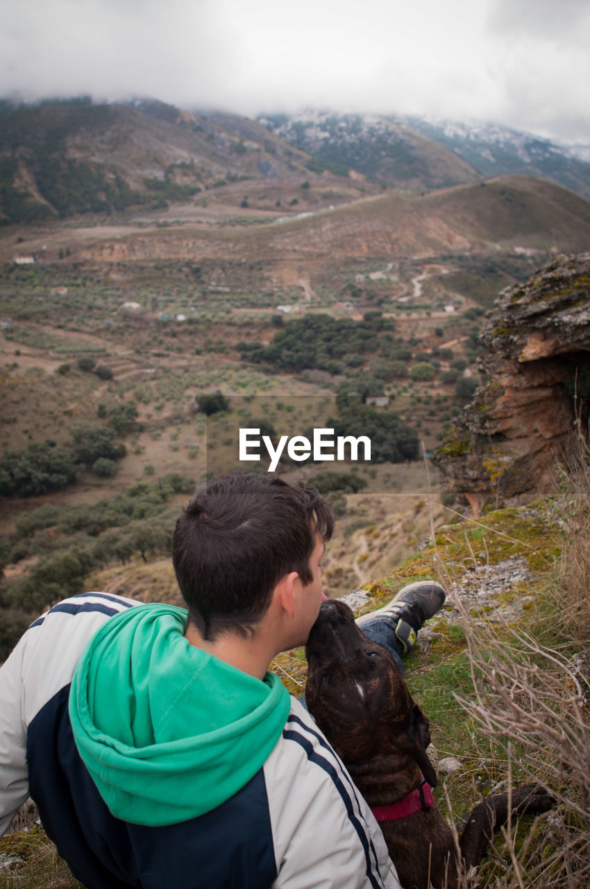 Young man with dog viewing mountains