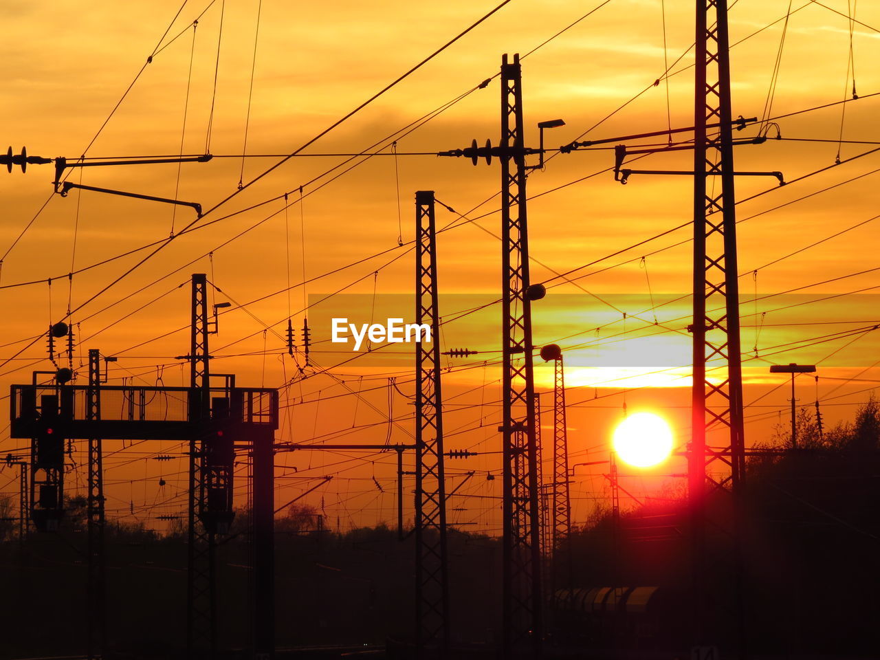 Silhouette electricity pylons at sunset