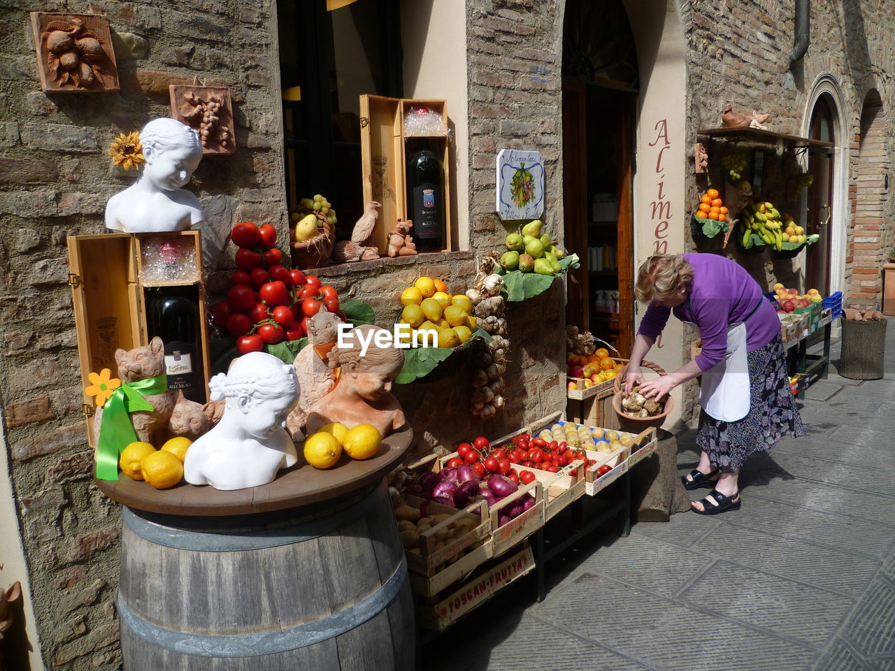 Woman sorting vegetables in front of store
